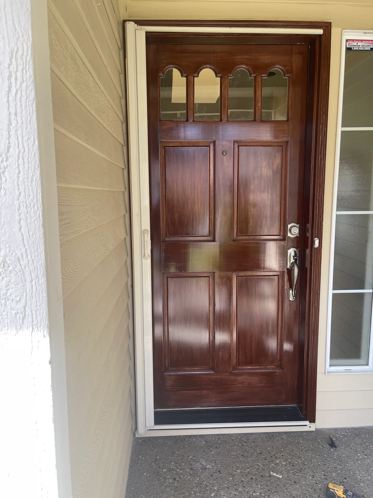 A richly stained wood front door with decorative glass panels
