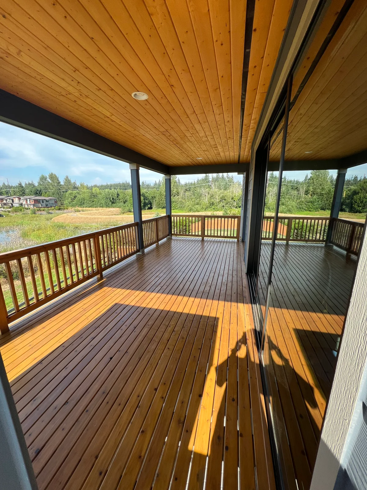A covered wooden deck with warm wood boards and a view of the garden
