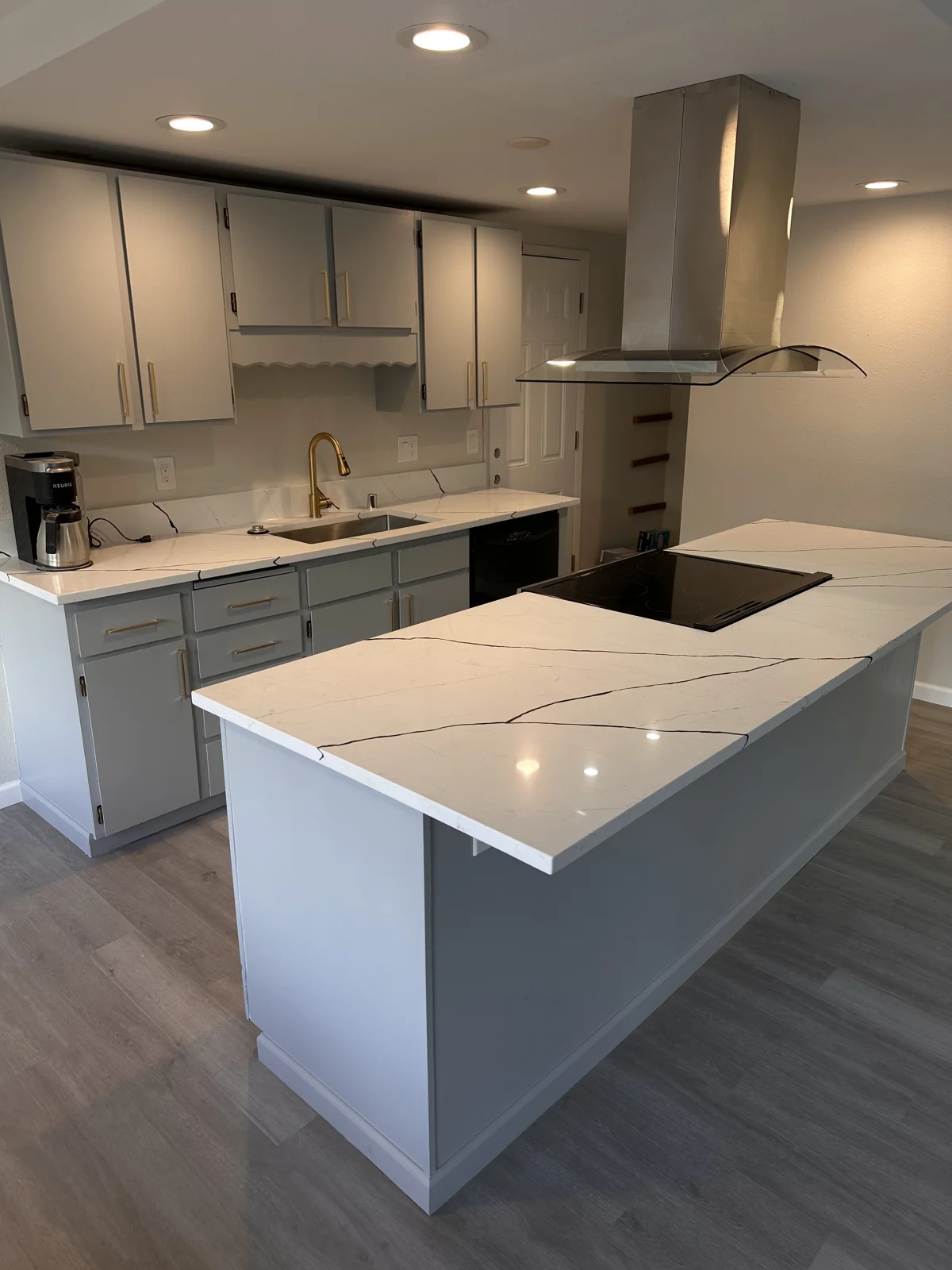 Blue-gray kitchen cabinetry, a white island countertop, and a stainless steel range hood