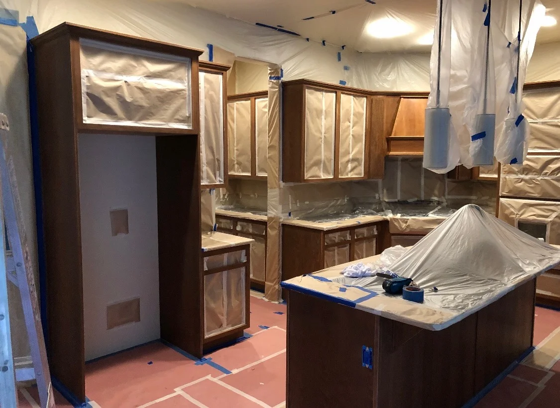 Kitchen cabinets masked with paper and plastic, with protected counters and flooring during preparation