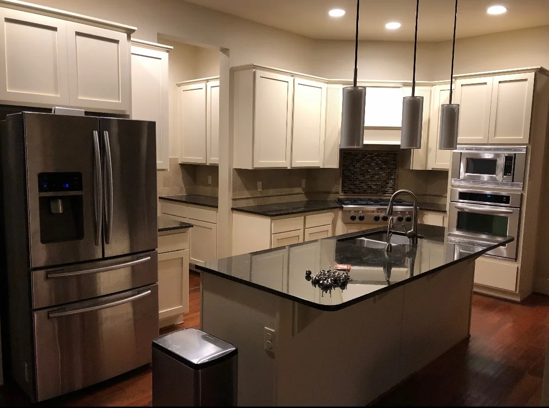 White kitchen cabinets surrounding a dark countertop and central island
